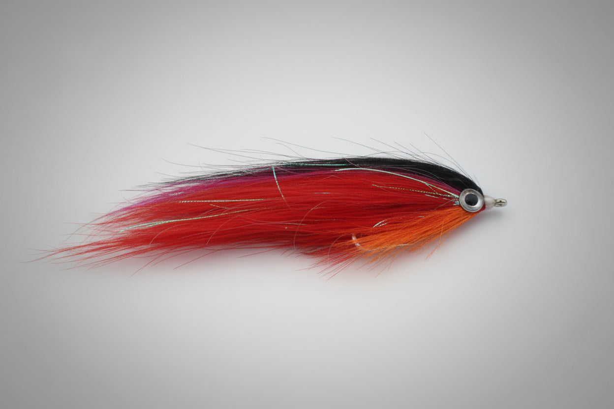 Red and black fly fishing lure on a dark brown background