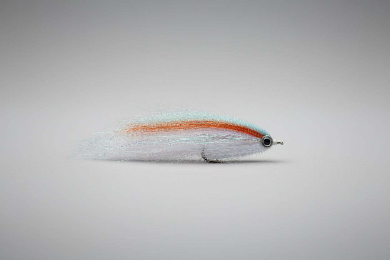 Fishing fly with white body and orange stripe on a dark brown surface